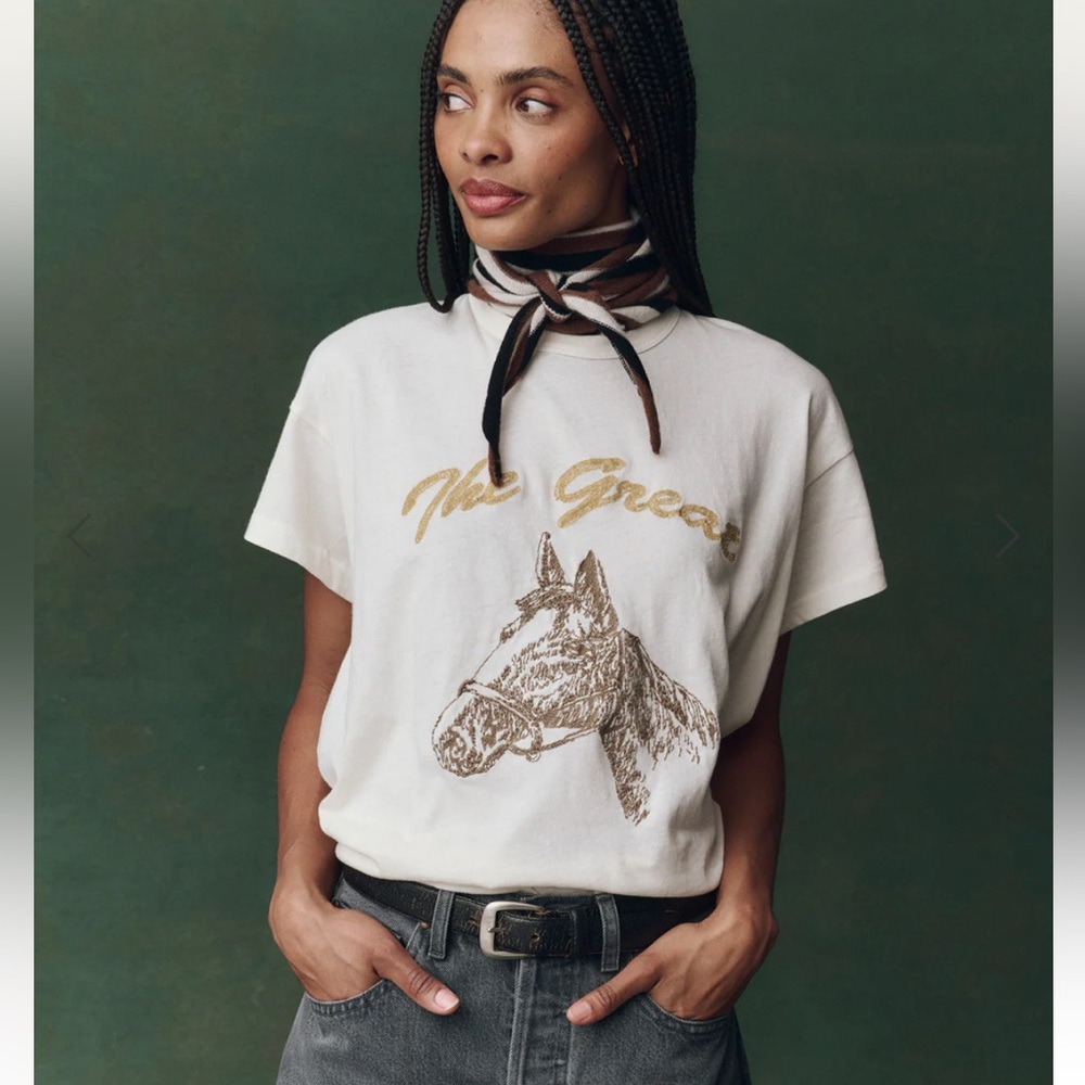 THE GREAT. Cream Short Sleeve Tee with Gold Script & Brown Horse Graphic